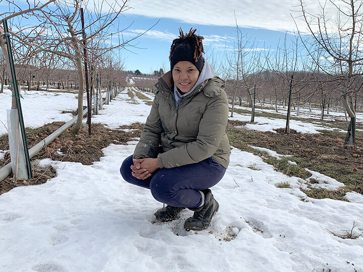 Female migrant worker Felena Pereira crouches in apple orchard
