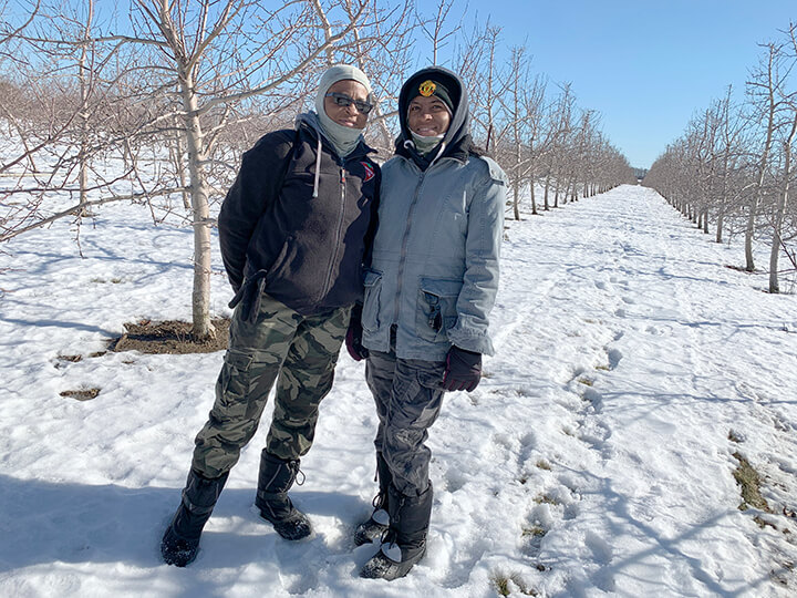 mother and daughter migrant workers pose for camera on a snowy day at the farm