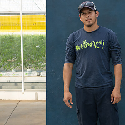 male migrant worker posing for camera, while standing in front of farm