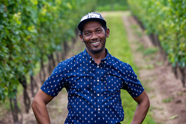 Migrant worker standing in vineyard smiling at camera