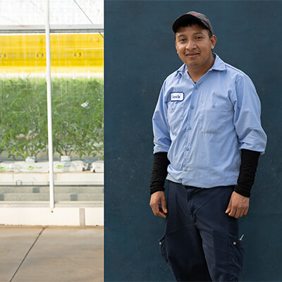 migrant worker, smiling for the camera in front of farm