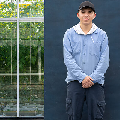 migrant worker posing for camera in front of farm