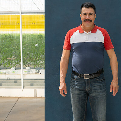 male migrant worker poses for camera while standing in front of farm