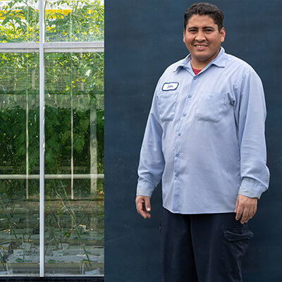 male migrant worker posing for camera while standing in front of farm