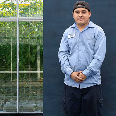 male migrant worker posing for camera in front of farm