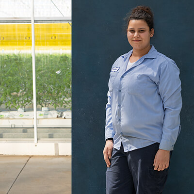 female migrant worker posing for camera while standing in front of farm