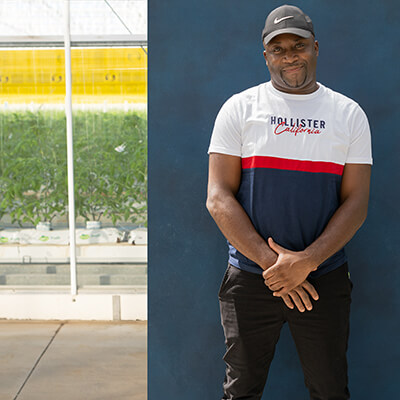 male migrant worker posing for the camera while standing in front of farm