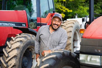 Migrant farm worker in front of a tractor