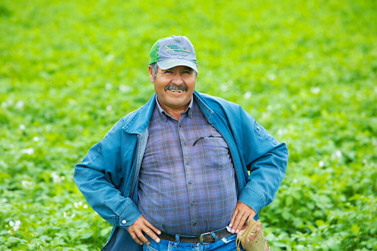 male migrant worker smiles for camera in farm field