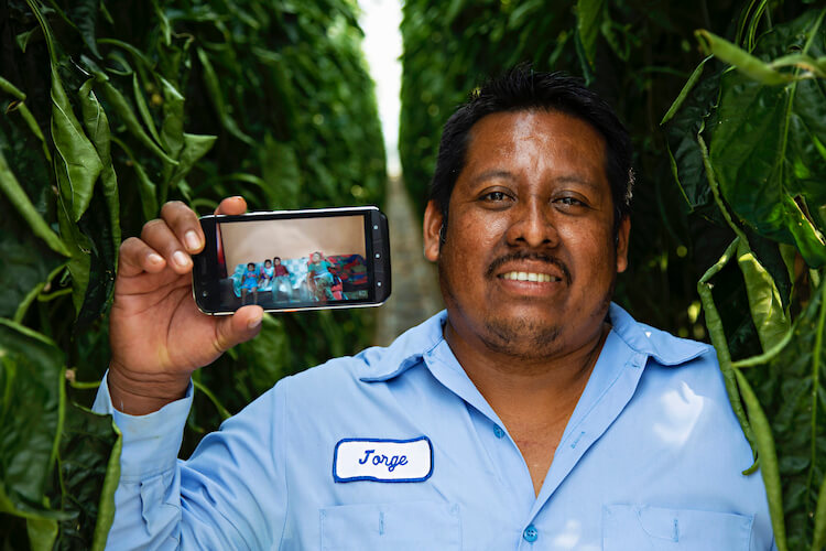 male migrant worker holds phone while smiling for camera