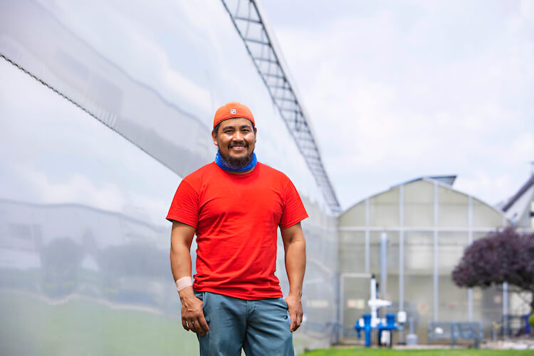 migrant worker smiling at camera while at farm