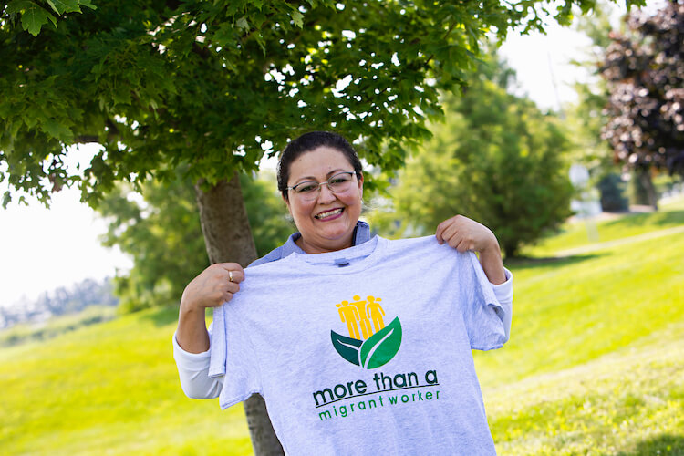 female migrant worker holing "More than a Migrant Worker" T-shirt