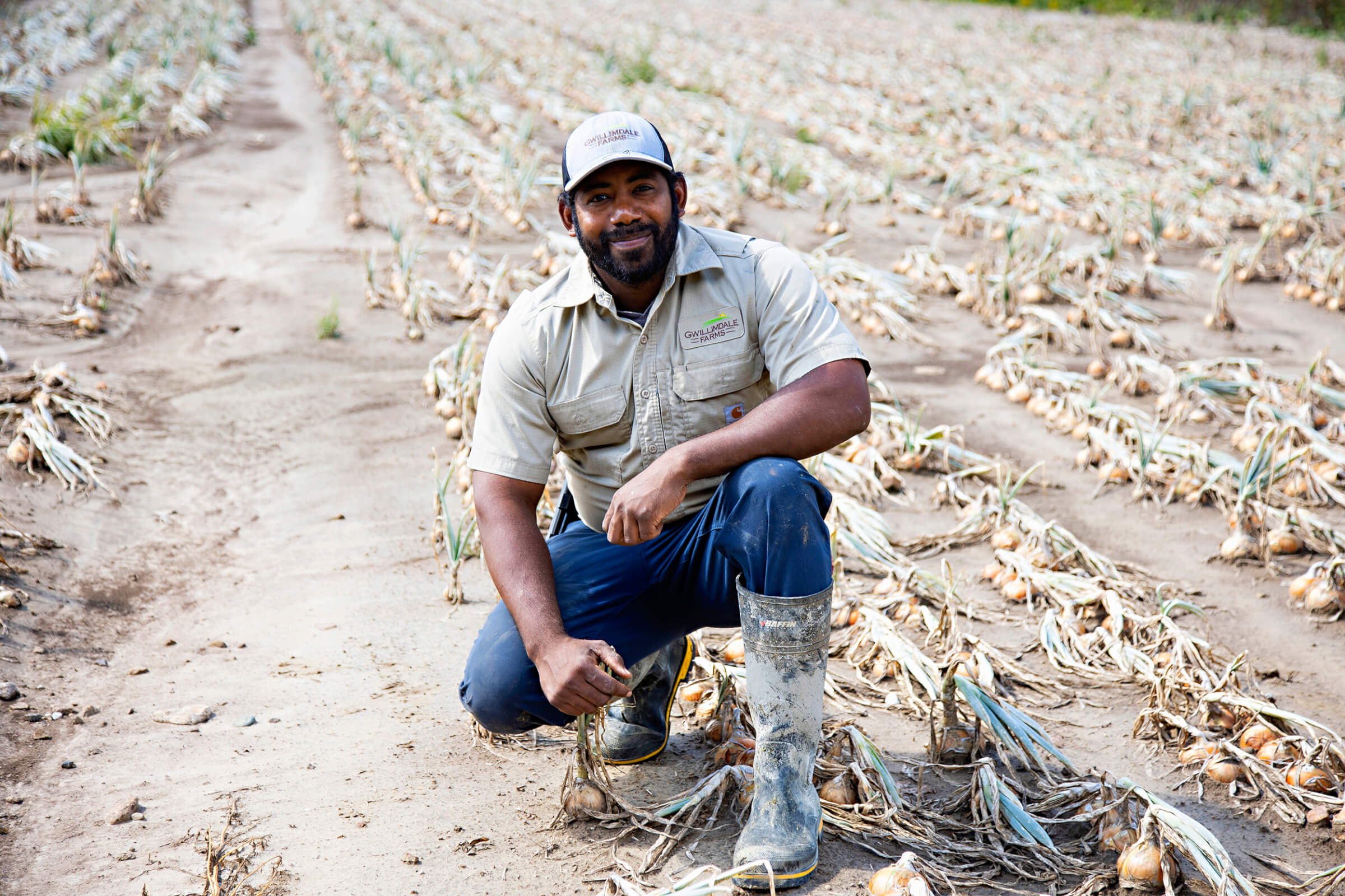 Migrant farm worker kneeling in a field looking at the camera