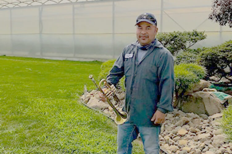 Migrant worker in front of greenhouse