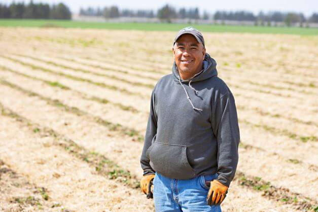 male migrant worker standing for camera in farm field