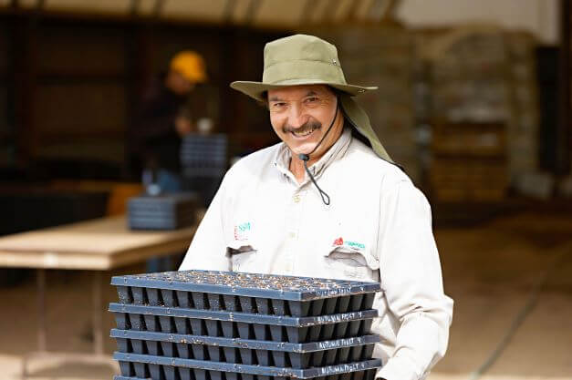 male migrant worker smiling for camera while holding flats