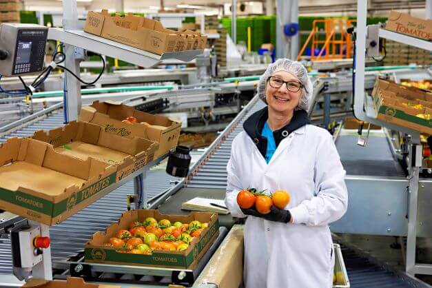 female farm worker smiles in greenhouse