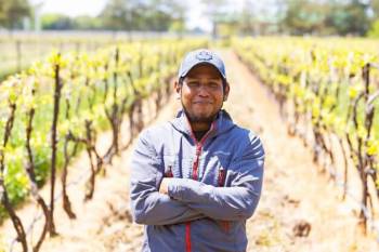 male migrant worker smiling for camera in farm field