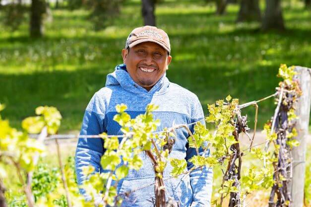 male migrant worker smiling for camera in farm field