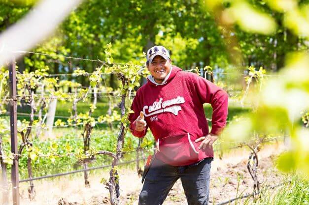 male migrant worker smiling for camera in farm field