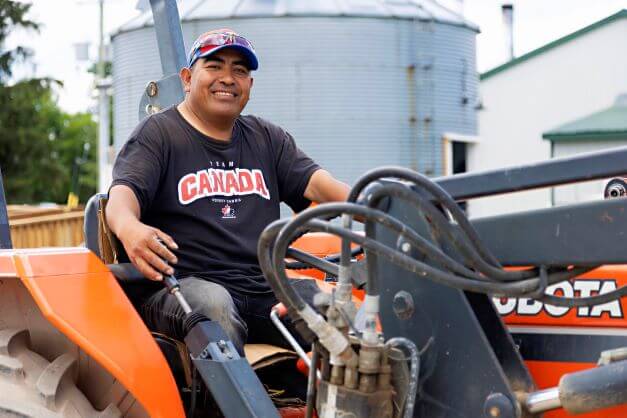 male seasonal agricultural worker sitting in tractor