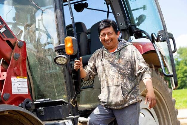 male worker standing on the side of a tractor