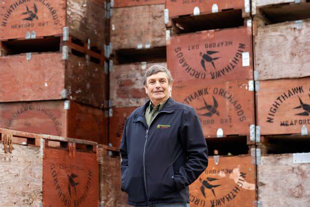 apple grower standing in front of crates