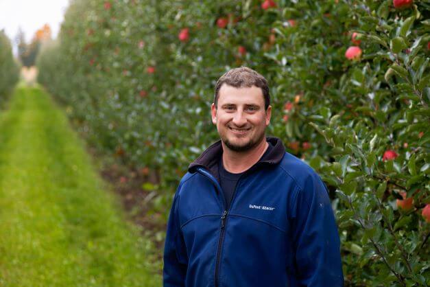 apple grower standing in orchard