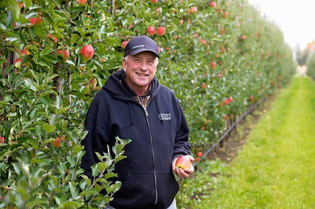 apple grower holding an apple while posing for camera